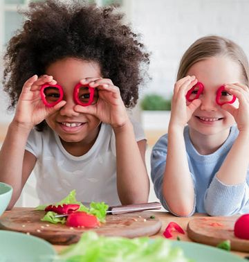 Kinder mit Gemüse für einen veganen Salat.