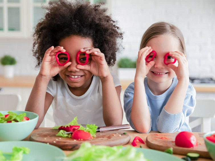 Kinder mit Gemüse für einen veganen Salat.