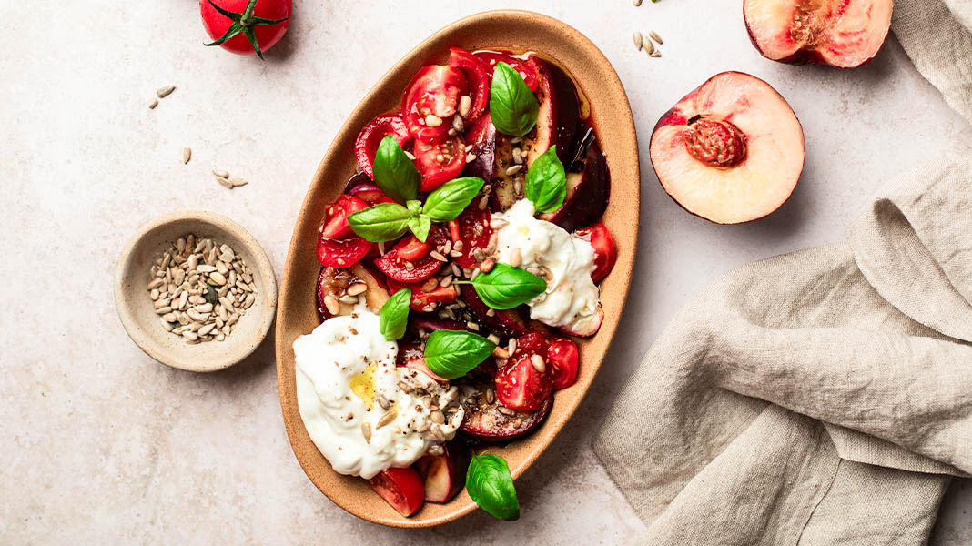 Frischer Basilikum an Burrata mit Pflaumen und Cherrytomaten